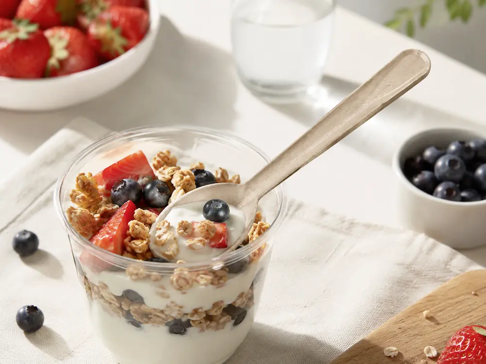 Natural-color 6-Inch Molded Fiber Spoon used with yogurt, granola, strawberries, and blueberries in a breakfast foodservice setting