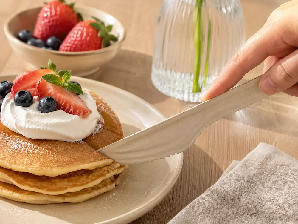 Natural-color 6-Inch Molded Fiber Knife cutting pancakes topped with cream, strawberries, blueberries, and mint in a breakfast setting